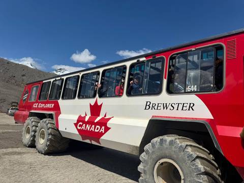 Massive Brewster Ice Explorer bus with passengers looks out onto the icefield under clear skies.