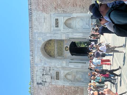 Crowds stream through the ornate marble entrance of Topkapi Palace on a bright day.