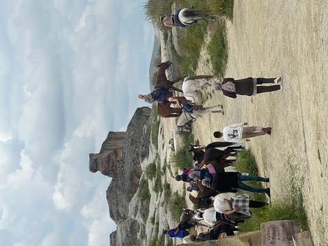 Tourists mount horses amid Cappadocia’s rolling hills and unique rock outcrops.
