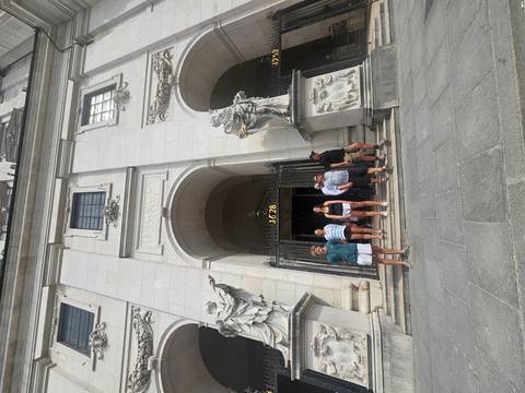 Travelers exit a grand stone church façade adorned with statues and baroque details.