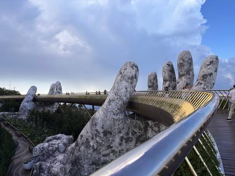 The famous Golden Bridge supported by giant stone hands stretches across misty treetops in Ba Na Hills.