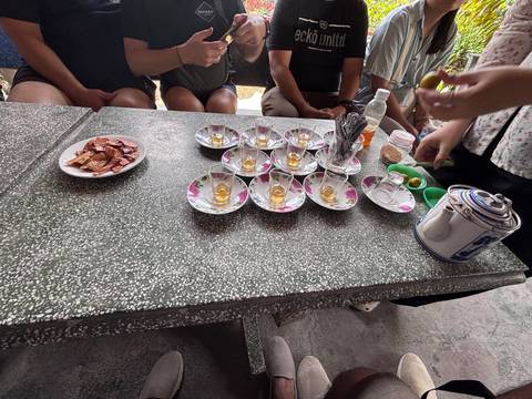 Small cups of honey tea and local snacks are arranged on a stone table during a Mekong rural tasting session.