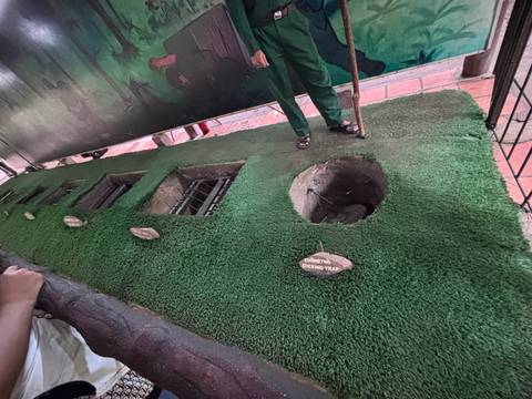 A demonstration pit lined with artificial grass shows traps used in the Cu Chi tunnels exhibit.