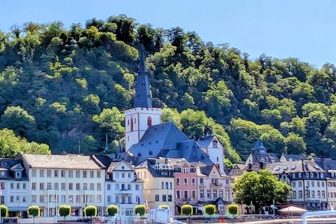 Colorful riverside town houses and church spire framed by green hillside