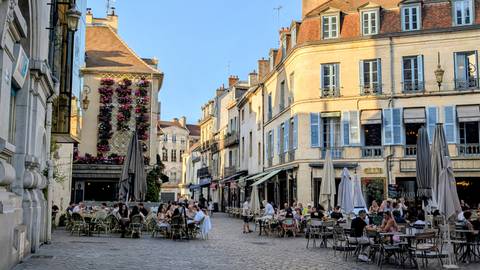 Bustling café-lined square with diners enjoying evening light in Dijon