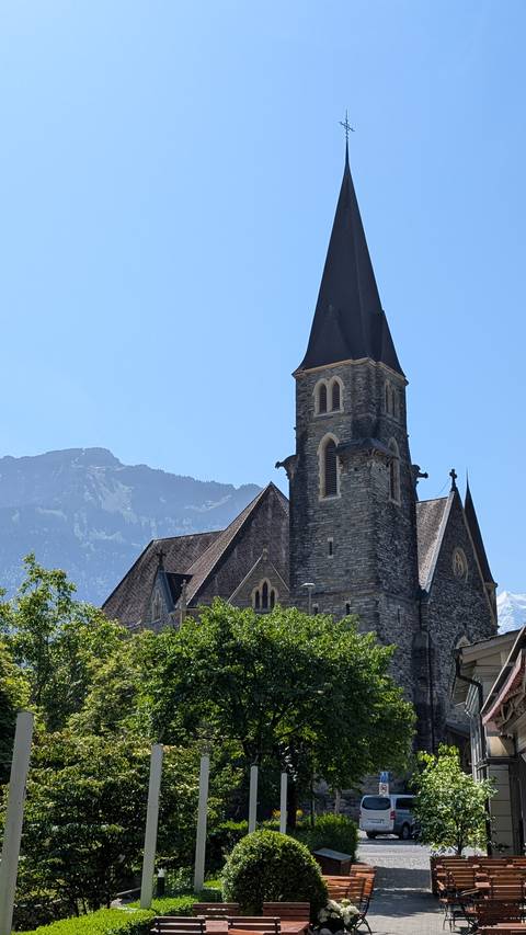Stone church with mountain backdrop under clear summer sky