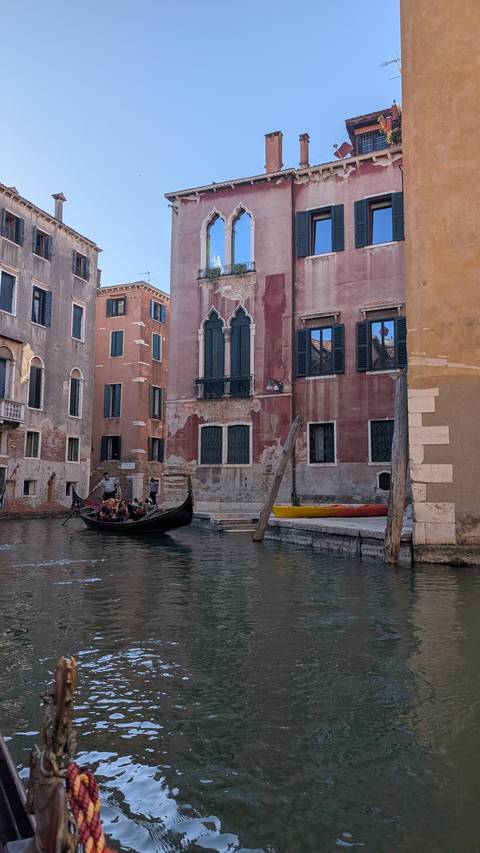 Gondolier steering passengers along quiet residential canal in Venice