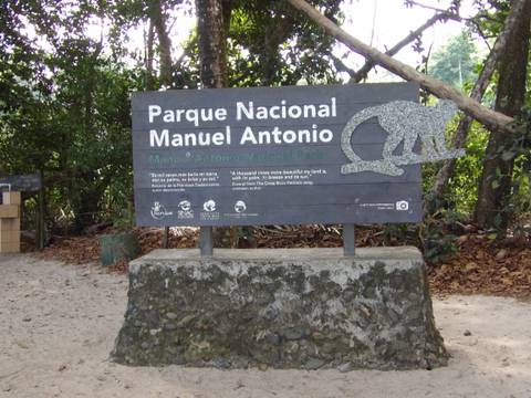 Entrance signboard for Parque Nacional Manuel Antonio surrounded by lush tropical forest.