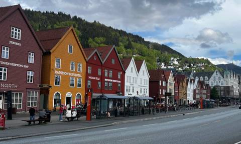 Iconic colorful wooden warehouses of Bryggen wharf in Bergen with busy street life below.
