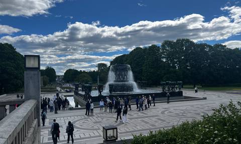 Crowds gather around Vigeland Park’s grand fountain under partly cloudy skies in Oslo.