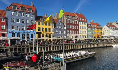 Colorful 17th-century houses along Copenhagen’s Nyhavn canal bustling with tour boats and cafés.