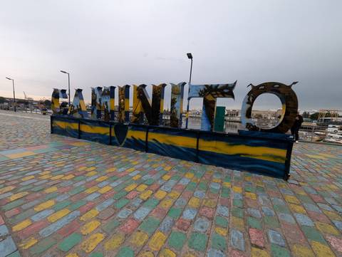 Large metal letters spelling 'CAMINITO' stand on a painted cobblestone promenade in Buenos Aires’ La Boca district under an overcast sky.