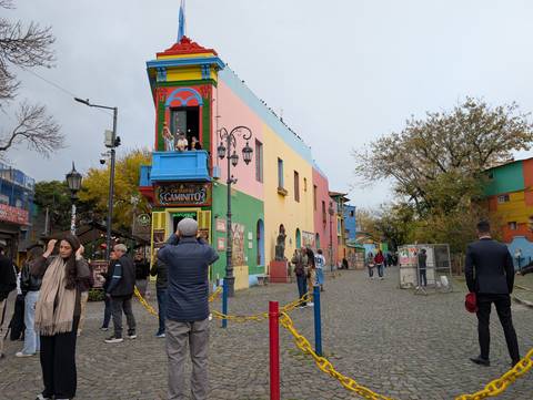 Color-blocked houses of La Boca line a pedestrian street as tourists stop to take photos of the colourful façades.