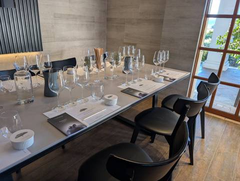 Elegant table set for a premium wine tasting with multiple crystal glasses and tasting notes in a contemporary room.