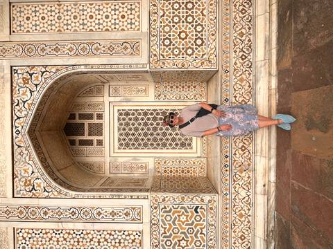 Traveler in front of intricately inlaid marble doorway at Itimad-ud-Daulah mausoleum in Agra.