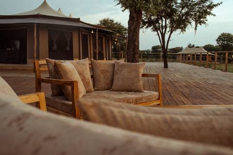 Comfortable outdoor lounge area on wooden deck of luxury tented safari camp.