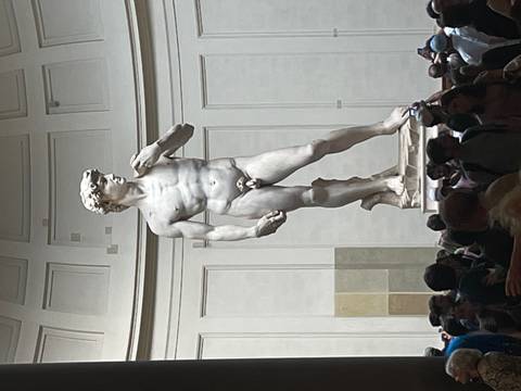 Michelangelo’s David stands majestically inside the Galleria dell’Accademia surrounded by visitors.
