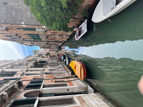 A tranquil narrow canal with moored boats reflects centuries-old Venetian buildings.