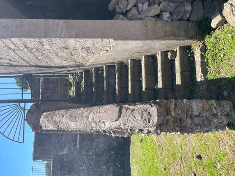 A weathered stone stairway ascends alongside an ancient wall in bright sunlight.