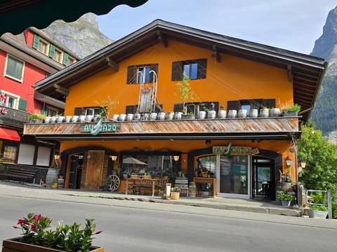 Charming orange chalet-style restaurant with wooden balcony barrels in an alpine village street