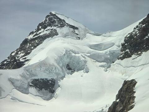 Close-up of dramatic snow-covered alpine peak with crevassed glacier slopes
