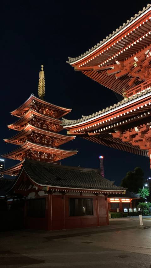 Illuminated five-story pagoda and ornate temple eaves glowing against the night sky in Tokyo