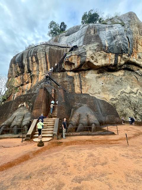 Visitors climbing the steep lion-paw staircase of Sigiriya rock fortress.
