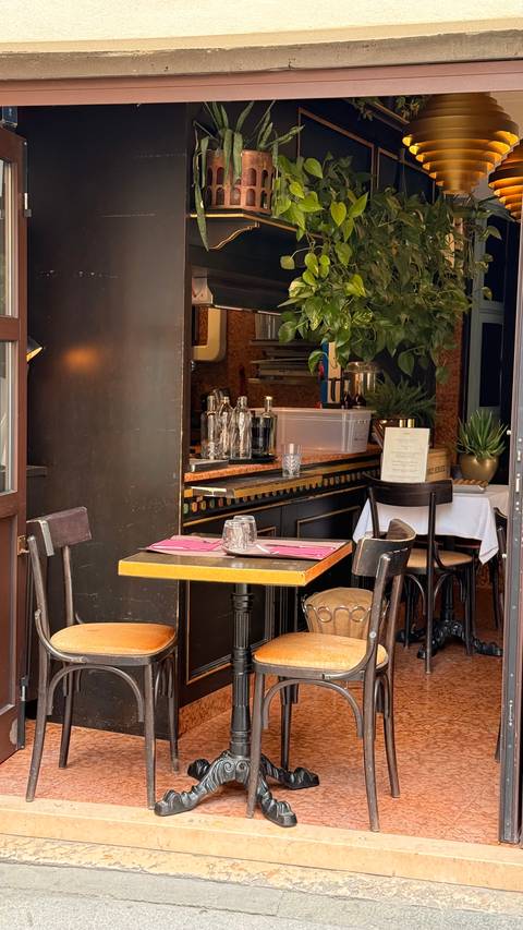 Cozy corner of a small restaurant with wooden tables, pink placemats and vintage décor.