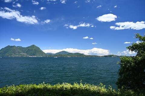 Wide expanse of deep blue lake under vibrant blue sky with scattered white clouds.