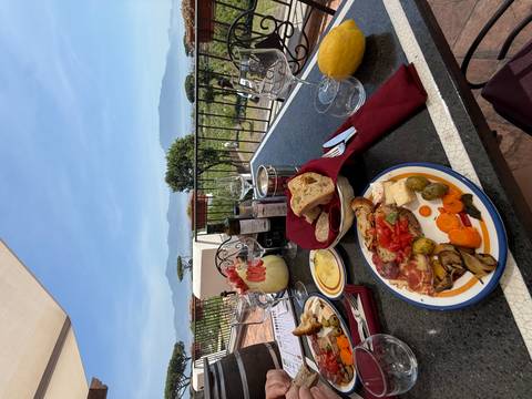 Italian antipasto plates and bread arranged on an outdoor terrace with coastal view
