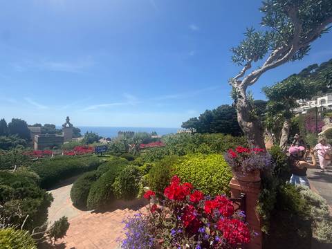 Lush Mediterranean garden with bright flowers, statues and sea glimpses below Capri