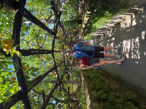 Couple stands beneath shady lemon arbor path surrounded by lush greenery in Amalfi