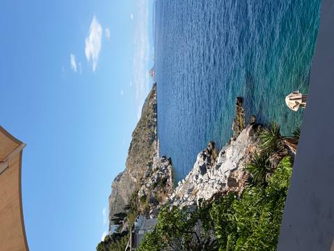 Rocky Mediterranean coastline with deep blue sea and distant island under a clear sky