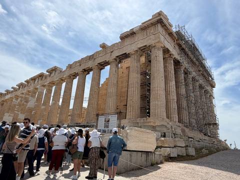 Crowd of tourists in front of the Parthenon’s massive columns under a partly cloudy sky