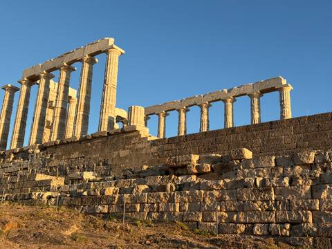 Sun-lit marble columns of the Temple of Poseidon towering above a rugged stone platform