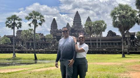 Couple posing in front of the iconic towers of Angkor Wat on a bright afternoon.