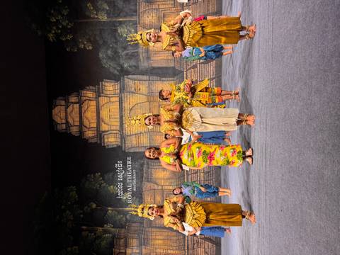 Traditional Apsara dancers in colorful costumes performing on a theatre stage set against an Angkor backdrop.
