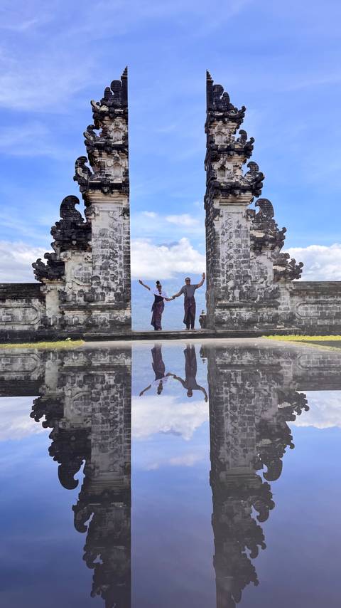 Couple framed by the Gates of Heaven with a mirror-reflection effect and mountains in the distance.