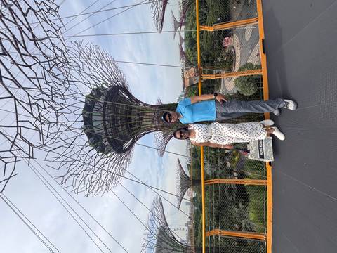 Couple on the OCBC Skyway with towering Supertrees rising behind them on a clear afternoon.