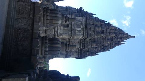 Detailed stone spire of a Prambanan temple rises sharply against a blue sky