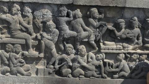 Intricate bas-relief carvings depicting ancient figures in stone panel at Borobudur