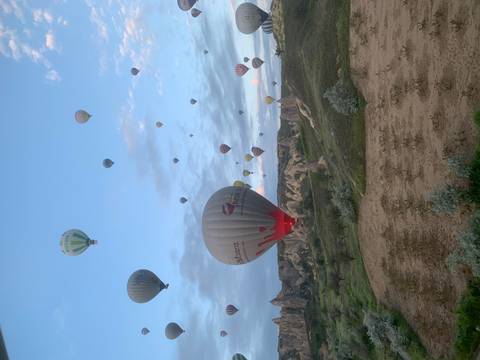 Numerous hot-air balloons of varying colors rise over Cappadocia’s spired landscape.