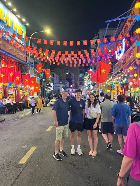Three travelers on a lively Vietnamese street at night under strings of red flags and lanterns.