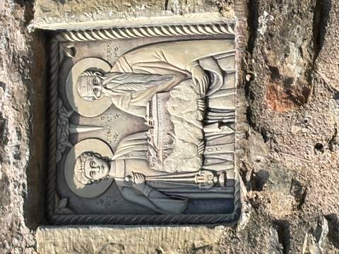 Stone relief depicting two saints holding a monastery, carved into a monastery wall.