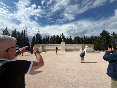 Travellers photograph the Leonidas monument under a dramatic sky at Thermopylae.
