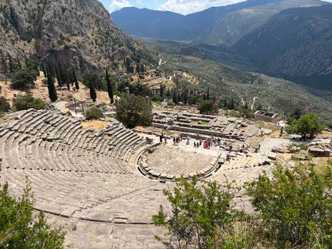 Panoramic view of the ancient stone theatre of Delphi nestled on a mountainside.