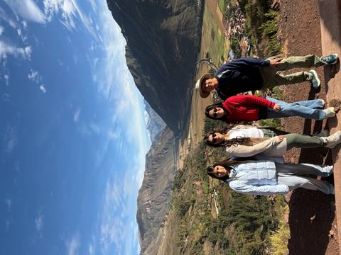 Family group posing before sweeping Andean mountains and fertile Sacred Valley landscapes.