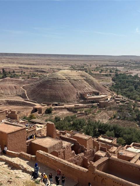 Arid hill and fertile valley seen from above with scattered traditional buildings in the foreground.