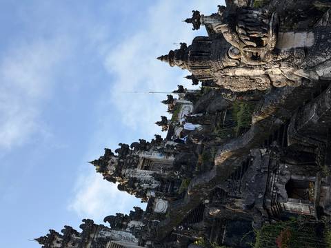 Ornate stone temple complex rising against a bright blue Balinese sky.