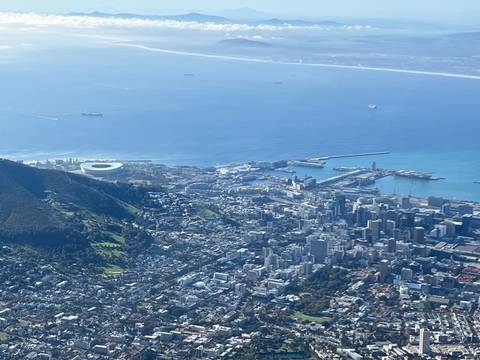 Aerial view of Cape Town with Lion's Head, the stadium and the city sprawling along the coastline under bright blue skies